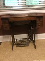 Front view of Singer cabinet closed showing drawers and treadle base