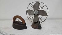 Cast iron iron and metal fan side by side
