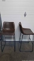 Two brown leather bar stools front view