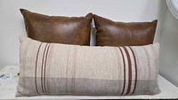 Front view of lumbar cushion and pair of brown faux leather cushions