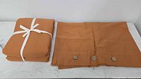 Folded duvet cover tied with white ribbon beside folded cover with three wooden buttons visible