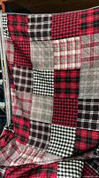 Front view of quilt showing red/black/white/grey patchwork design