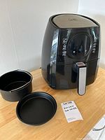 Front view of Kalorik air fryer with basket and crisper plate beside it