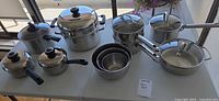 Full set of pots, lids, steamer insert, and mixing bowls on table
