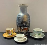 Group shot of vase and three teacup-saucer sets