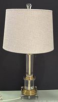 Full view of plexiglass and brass-tone table lamp with shade
