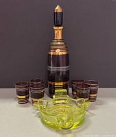 Front view of full set showing decanter, six shot glasses, ashtray