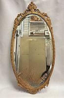 Front view of ornate gold oval mirror