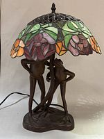 Full view of lamp illuminated showing stained glass shade and frog base