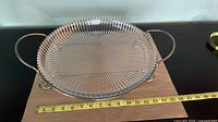 Dish seated in metal stand, measuring tape shows scale