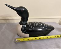 Side profile of wooden loon with tape measure showing length