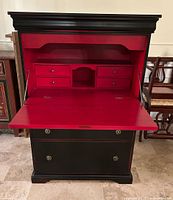 Front view with drop front open showing red interior drawers and cubby