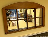 Full view of wooden arched window-style mirror on wall