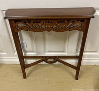 Front view of wooden console table showing decorative apron and legs