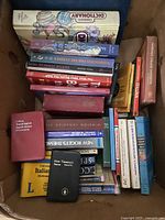Box containing assorted books stacked vertically and horizontally