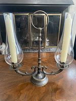 Front view of brass two-arm candelabra with glass shades and candles