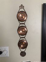 Full view of copper wall hanging showing three plates and bottom medallion