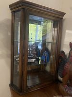 Angled frontal view showing overall cabinet, wood frame, glass door, side panels