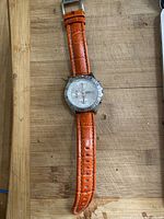 Full view of Fossil chronograph watch with orange leather band on wood surface