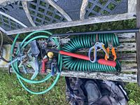 All items on bench: hoses, sprinkler, pruners, hoe, nozzles, trowel, wand