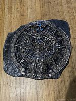 Front view of cast metal Aztec calendar plaque on stone-textured base