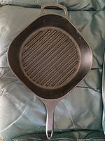 Top view showing square ridged cooking surface, long handle, helper handle