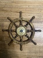 Full view of wooden ship’s wheel barometer placed on floor