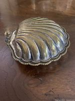 Closed shell-shaped silver dish exterior