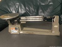 Full view of grey Ohaus triple beam balance showing platform and beams