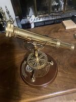 Side view showing full brass telescope and ornate mount on wooden base
