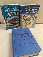 All three Prudence Penny cookbooks standing on table