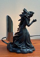 Left side view of sculptural lamp showing figure detail and cord