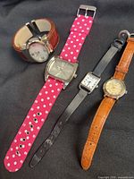 Four wristwatches laid out showing dials and straps