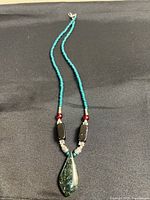 Full view of entire necklace laid flat showing bead sequence and pendant