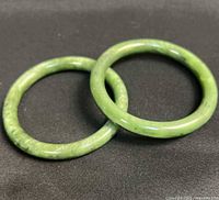 Two green stone bangles overlapped on black background