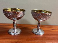 Pair of silver-plated coupes on wood surface