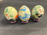 Front view of three hand-painted eggs on wood stands