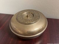 Angle view of rounded brass bowl with lid on showing overall shape