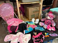 Overview of bear clothing, shoes, robe, carrier seat and accessories on table