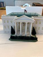 Front view of ceramic White House model with flag and shrub detail