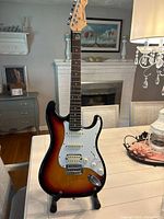 Full front view of Donner sunburst electric guitar on stand