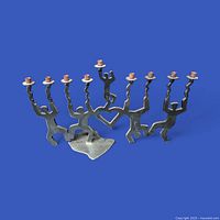 Front view of entire metal menorah showing nine candle cups and dancing figures