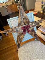 Full view of large wooden star with plaid bow displayed on chair