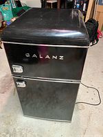 Front view of black Galanz two-door mini fridge, power cord visible