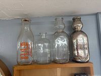 Group shot of four antique glass milk bottles on shelf