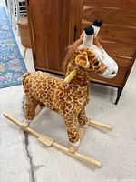 Full side view of plush giraffe on wooden rocker base