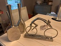 Two silver vases and bicyclist sculpture grouped on table
