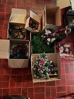 Overview showing six open boxes containing two boxes of string lights, artificial greenery and ornaments