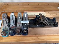 Group of six bench planes on workbench