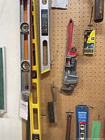 Pegboard view showing three spirit levels, pipe wrench, wire brush